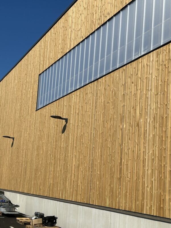 En snygg lagerbyggnad med träfasad och kanalplastskivor som ljusinsläpp